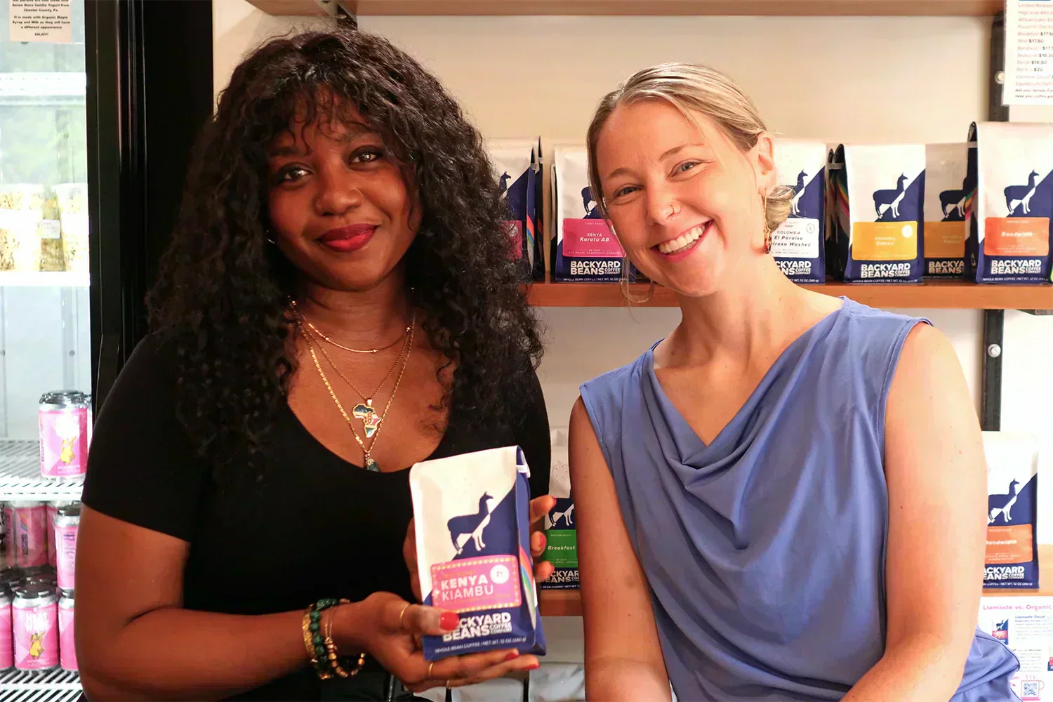 Image of two women holding bag of coffee with coffee shelves in the background