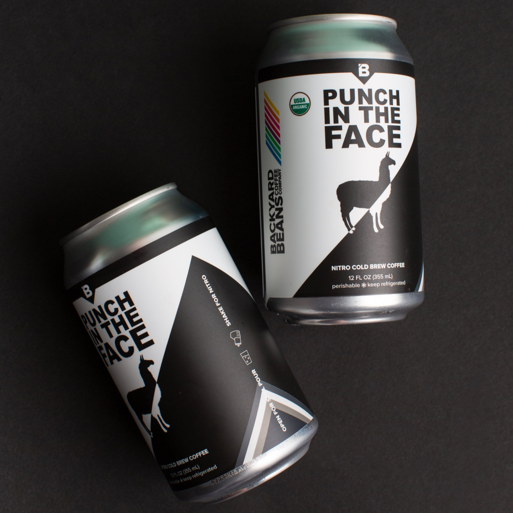 Two cans of 'Punch in the Face' coffee on a black background