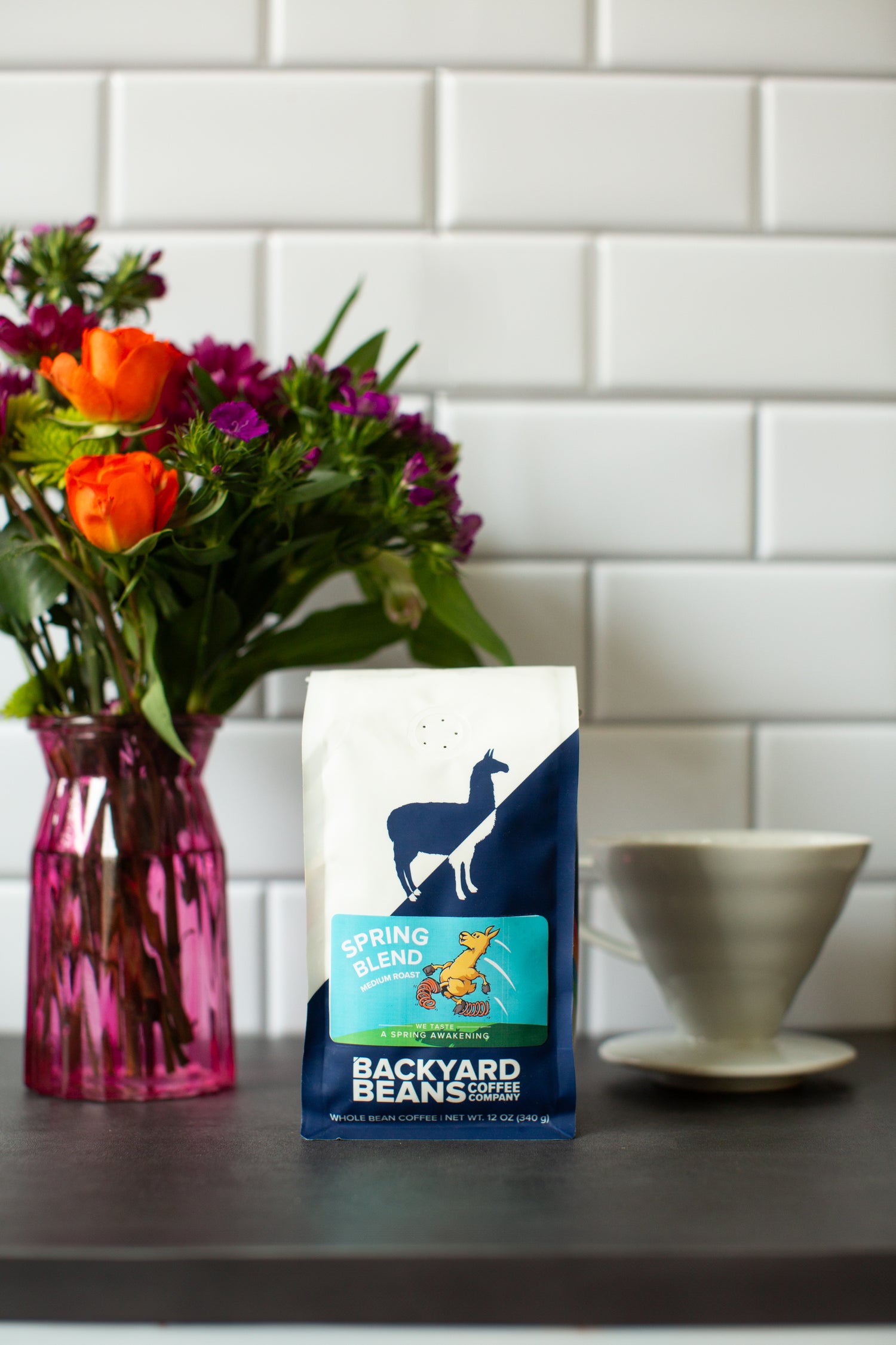 Image of Spring Blend coffee bag on kitchen counter with flowers and pour over.
