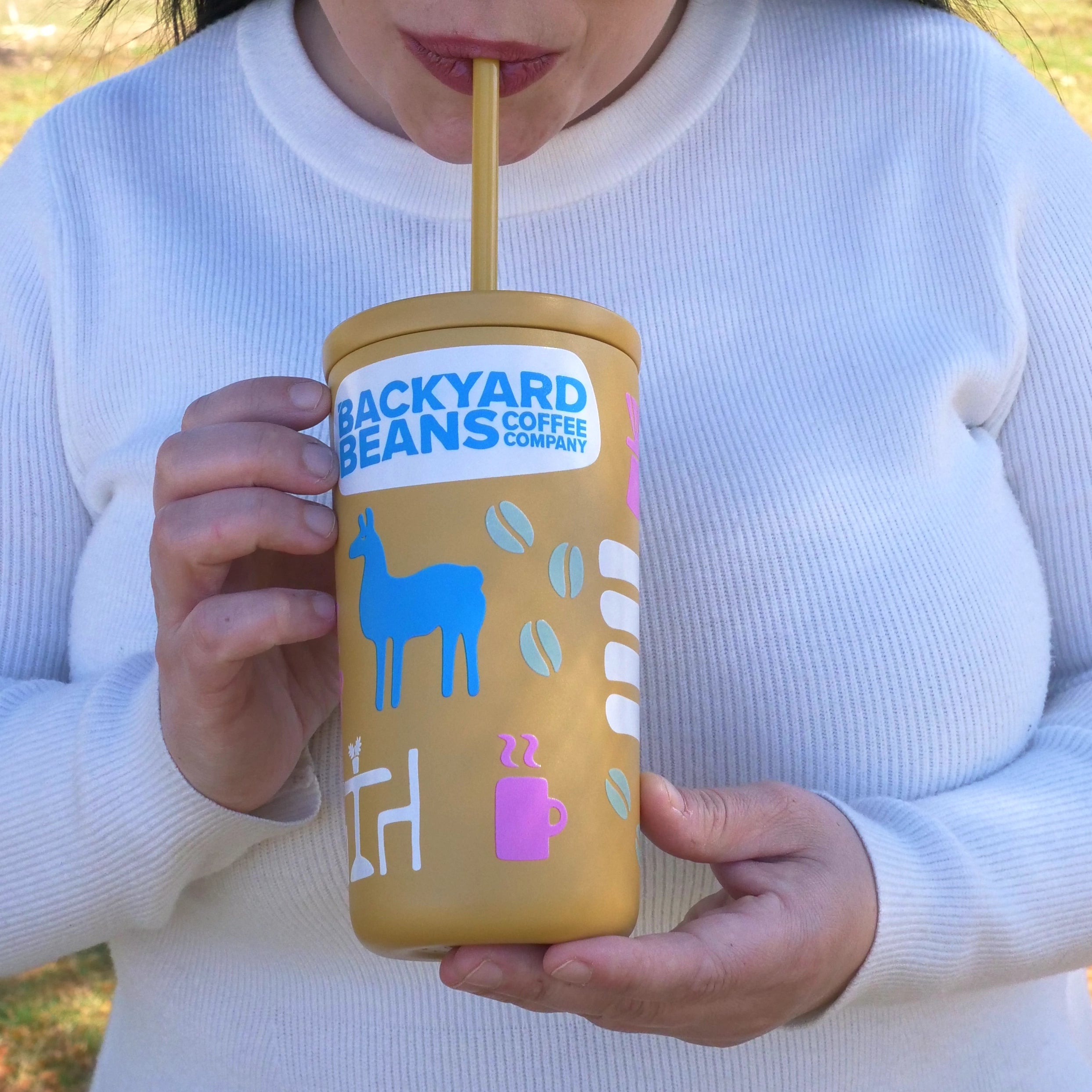 Image of woman sipping Backyard Beans yellow spring cold cup