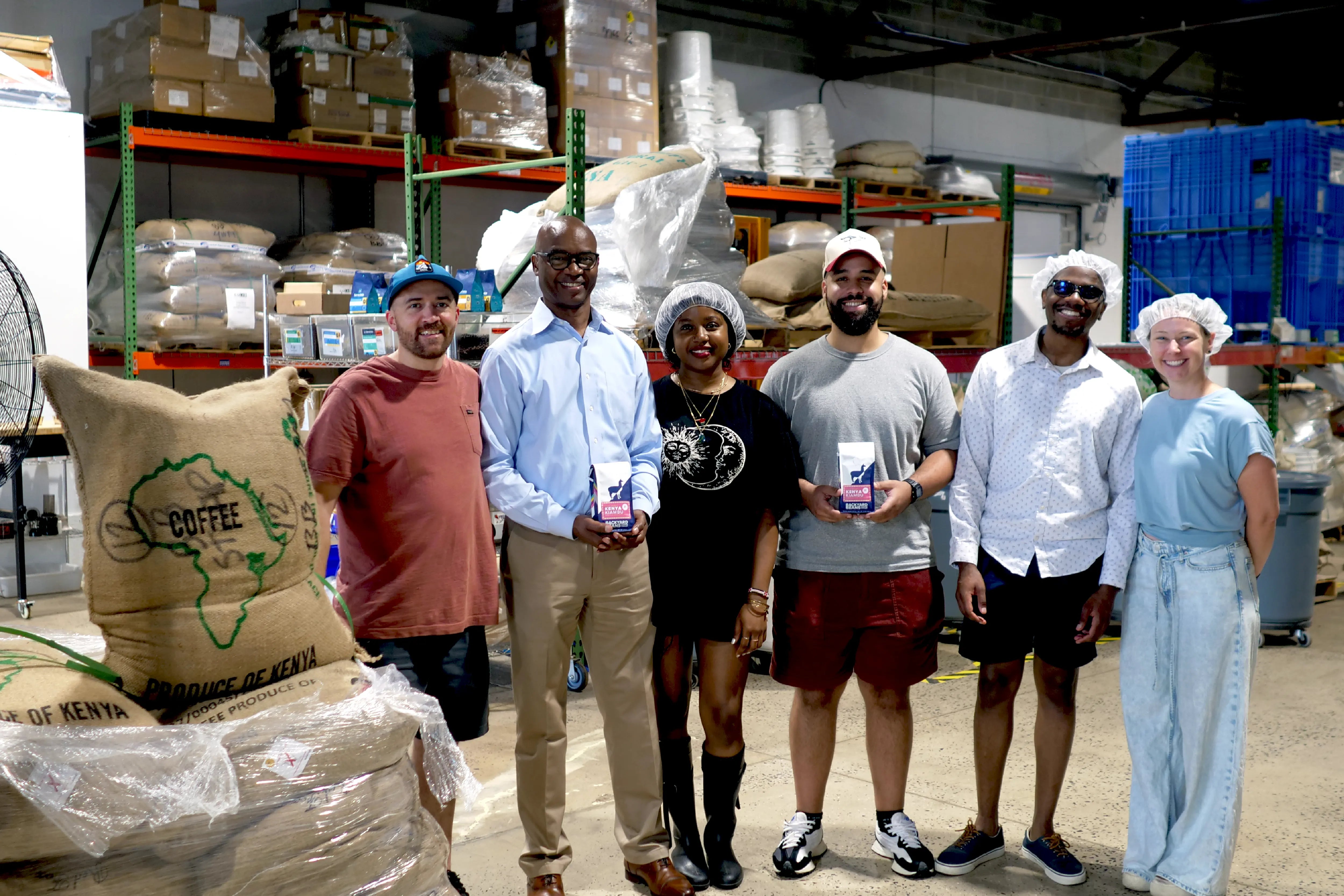 Image of Backyard Beans and Anaweza Team holding bags of coffee next to burlap coffee bag