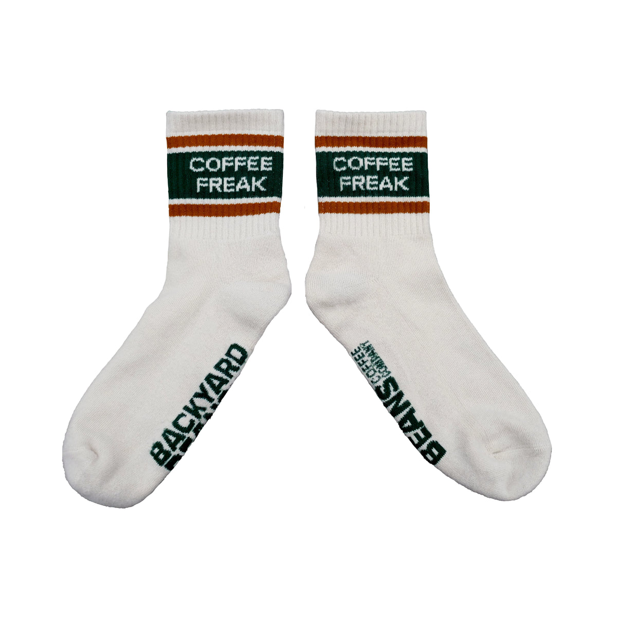A pair of white crew socks with dark green and orange stripes at the cuff, featuring 'COFFEE FREAK' printed in white on the green band, and 'BACKYARD BEANS' printed vertically in dark green on the sole of each sock.